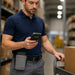 Warehouse worker using an Almex mobile computer with gray small waist belt case attached for secure device carrying during inventory tasks.