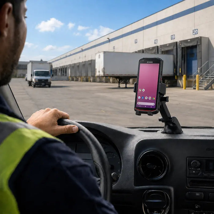 Keyence scanner mounted in a dashboard vehicle cradle inside a delivery vehicle near an outdoor warehouse loading dock.